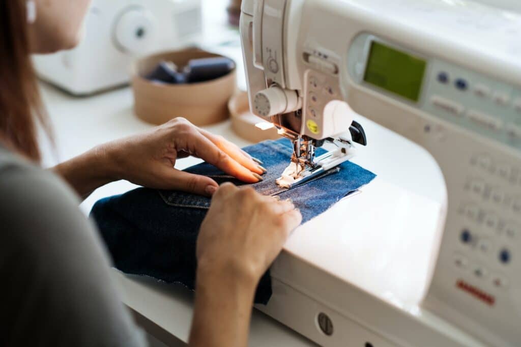 Reuse, repair, upcycle. Denim upcycling ideas, repair and using old jeans. Close-up of sewing